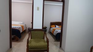a room with a chair and a bedroom with two beds at Departamento Macas in Macas