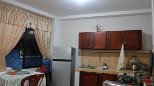 a kitchen with a white refrigerator and wooden cabinets at Departamento Macas in Macas