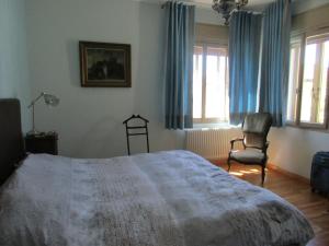 a bedroom with a bed and a chair and windows at CASA ROMAN ITALIA, Center Sacile in Sacile