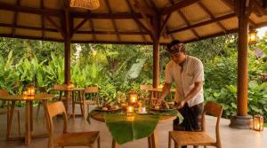 a man standing at a table with a plate of food at Sananda Aryani in Lovina