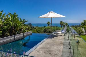 a swimming pool with an umbrella and two chairs next to it at L'Appartement Bleu in Waiheke Island