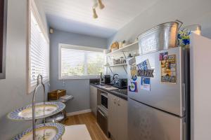 a kitchen with a stainless steel refrigerator and two tables at L'Appartement Bleu in Waiheke Island