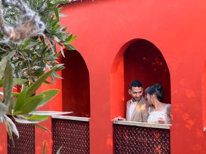 a bride and groom looking out the window of a red building at iBiZa Hostel in Beni Suef