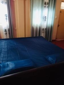 a bed with blue sheets in a bedroom with curtains at Lagoon Stay in Moraketiara