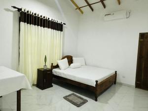 a white bedroom with a bed and a window at Sigiri Gateway in Galewela