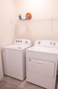 a laundry room with two white washes and a shelf at South Shore Suites in Wimauma