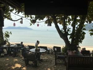 a man standing at a table on the beach at Green Garden Bungalow Resort in Ban Khlong Kloi