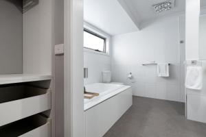 a white bathroom with a tub and a sink at Happy Tails Devonport in Devonport +31 photos