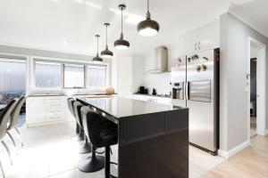 a kitchen with a black island in a kitchen with a refrigerator at Happy Tails Devonport in Devonport