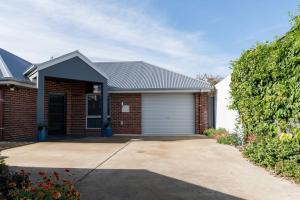 a red brick house with a white garage at Happy Tails Devonport in Devonport