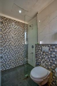 ein Badezimmer mit Toilette und Glasdusche in der Unterkunft Hotel Sea Sapphire in Calangute + 67 Fotos