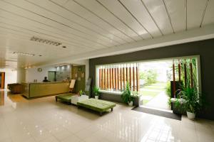 a lobby with a green couch and tables and plants at Naraséna Co-Living in Yogyakarta