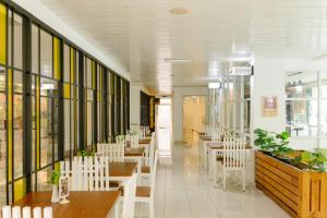 a restaurant with white chairs and tables and windows at Naraséna Co-Living in Yogyakarta