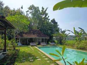 a villa with a swimming pool in a garden at Blauwtuin Yogyakarta in Yogyakarta