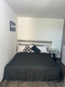 a bedroom with a bed with black sheets and pillows at comfortable and nice loft, great location in Aguascalientes