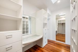 a white walk in closet with white cabinets and a mirror at Beachside Bliss - Ocean View, Pool, Sauna in Peregian Beach