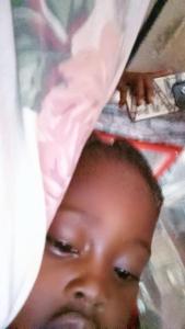 a young man is peeking out from under a bed at jeanrenald in Anse-à-Pitres