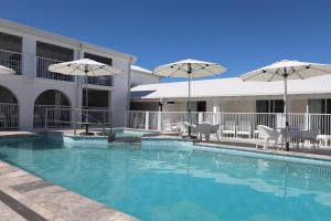 a swimming pool with chairs and umbrellas next to a building at Don Pancho Beach Resort in Bargara