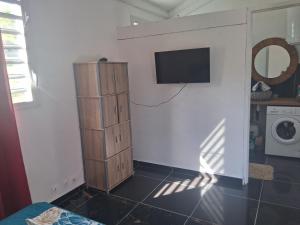a room with a tv on a wall with a shelf at Kaz o ti plezi in Sainte-Rose