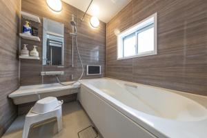 a bathroom with a tub and a sink and a window at A Family Friendly Spacious Villa - Easy to Tokyo Station & Conveniently Located for Tokyo Disney Resort & 1 min to Convenience Store in Tokyo