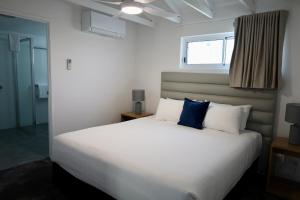 a bedroom with a large white bed with blue pillows at Don Pancho Beach Resort in Bargara +24 photos
