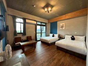 a hotel room with two beds and a desk and windows at Bear&Best Homestay in Yuli