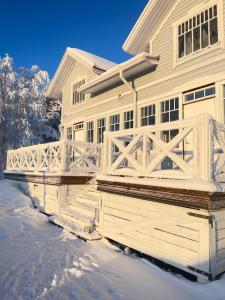 a house with a white fence in the snow at Villa Hirsipirtti in Rovaniemi