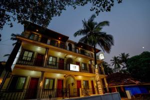 a large building with a palm tree in front of it at Casa Nathan in Calangute