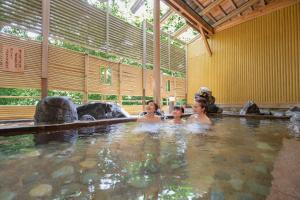 three women swimming in a hot tub in a building at Ooedo Onsen Monogatari Yamanaka Saichoraku in Kaga