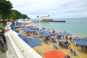 una playa con sombrillas azules y gente en la arena en One-bedroom Apartment with Sea view and View to Farol da Barra Praiaville, en Salvador