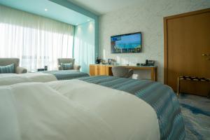 a hotel room with two beds and a television at Symphony Style Hotel Kuwait in Kuwait