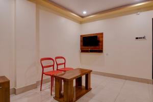 a room with two red chairs and a table and a tv at FabHotel Iubit in kolkata