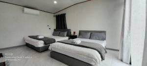 two beds in a room with white walls at lnthanon Laoju เล่าจู in Ban Na Yang