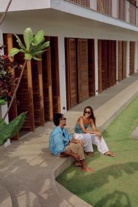 a man and woman sitting on the grass in front of a building at UNU Boutique Hotel -- Adults Only -- in Ahangama