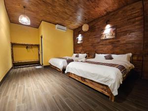 a bedroom with two beds and a wooden wall at PiTu Homestay in Dồng Văn