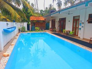 a large blue swimming pool next to a house at Coconut Villa in Bentota