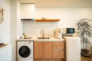 a kitchen with a washing machine and a refrigerator at Stay Cherry in Seogwipo