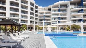 an image of a hotel swimming pool with chairs and a building at Oceanview Oasis in Urangan