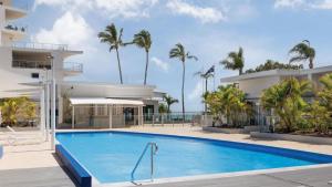 a pool in front of a building with palm trees at Oceanview Oasis in Urangan +35 photos