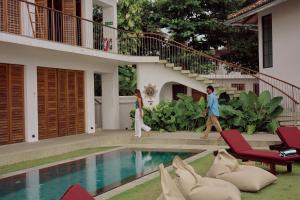 a man and woman walking by a swimming pool in a house at UNU Boutique Hotel -- Adults Only -- in Ahangama +111 photos