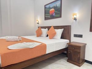 a bedroom with a large bed with white sheets and orange pillows at Dilaro Rest & Villa in Kottagoda