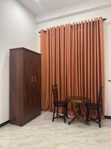 a room with a table and two chairs and a wooden cabinet at Dilaro Rest & Villa in Kottagoda