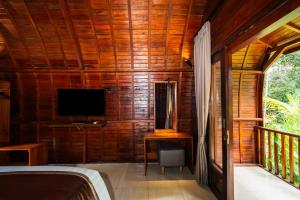 a bedroom with a bed and a tv on a wooden wall at Udaka Retreat in Payangan +28 photos