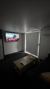 a room with a table and a tv on the wall at Tiny Home in Mosgiel in Mosgiel +20 photos