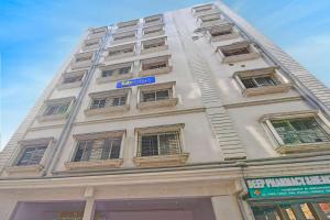 a tall white building with a blue sign on it at FabHotel Disa in kolkata
