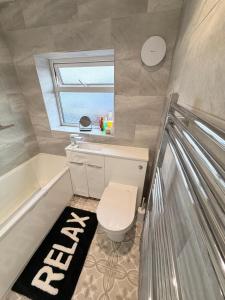 a bathroom with a toilet and a tub and a window at Precious House 2 in Leicester