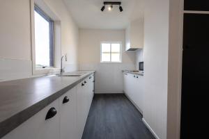 a kitchen with white cabinets and a sink and a window at Clock Tower Accommodation in Hokitika