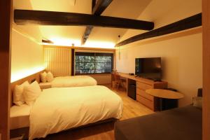 a hotel room with two beds and a television at HATAGO HIKONE - Annex in Hikone +6 photos