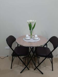 a round table with two chairs and a vase of flowers at The Suite Pod I CDO CondoStaycation - U26 in Cagayan de Oro