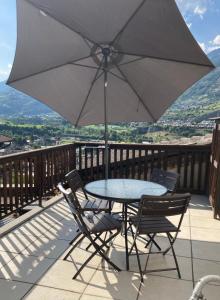 a table and chairs with an umbrella on a balcony at La maison de Linanna in Aymavilles
